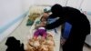 FILE - A woman helps her son as he lies on a bed at a cholera treatment center in Sanaa, Yemen, June 6, 2017.