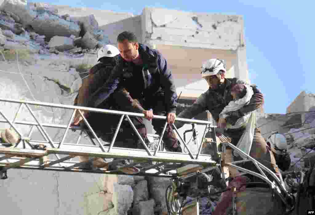 Relawan Suriah mengevakuasi seorang bayi dari reruntuhan pasca serangan udara Rusia di Idlib.