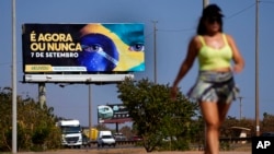 Una valla publicitaria se eleva sobre un sendero para correr con un mensaje que dice en portugués; "Es ahora o nunca, 7 de septiembre", en apoyo al llamado del presidente Jair Bolsonaro a sus simpatizantes para unirse a las celebraciones del bicentenario, en Brasilia, Brasil, el martes 6 de septiembre de 2022. Brasil celebra el bicentenario de su independencia el miércoles 6 de septiembre 7. (Foto AP/Eraldo Peres)