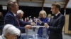 French President Emmanuel Macron casts his ballot flanked by French First Lady Brigitte Macron at a polling station to vote in the second round of French parliamentary elections in Le Touquet-Paris-Plage, July 7, 2024. 