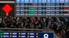 Travelers with luggage walk beneath a trains departure board as they arrive at the West Railway Station to catch their trains, in Beijing, Feb. 7, 2024. 