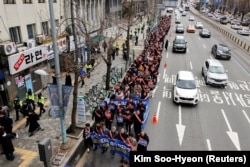 แพทย์ในเกาหลีใต้เดินขบวนมุ่งหน้าไปยังทำเนียบประธานาธิบดีในกรุงโซล เพื่อประท้วงนโยบายรับแพทย์ฝึกหัด เมื่อวันที่ 25 ก.พ. 2024 (ภาพจากรอยเตอร์)