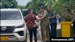 ໃນພາບທີ່ໄດ້ຈາກວີດີໂອ ໂດຍແຫຼ່ງຂ່າວທີ່ບໍ່ປະສົງອອກນາມ, ນຶ່ງໃນສອງນັກເຄື່ອນໄຫວ, ຊ້າຍ, ເດີນທາງກັບນັກກົດໝາຍເພື່ອສິດທິມະນຸດຊາວຈີນ ທ່ານລູ ຊີເວ, ຂວາ, ໂຕ້ຖຽງກັບຕໍາຫຼວດ ທີ່ກໍາລັງຈັບ ທ່ານລູ, ວັນທີ 28 ກໍລະກົດ 2023. (Anonymous Source via AP)