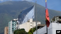 Bendera Venezuela dan PBB berkibar di sebuah gedung tempat badan HAM PBB berkantor di Caracas, Venezuela, Kamis, 15 Februari 2024. (Foto: AP Photo/Matias Delacroix)