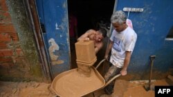 Para warga tampak membersihkan lumpur yang menggenangi rumah mereka di distrik Juquehy, Sao Sebatiao, Brazil, pada 20 Februari 2023, setelah hujan deras menyebabkan banjir dan tanah longsor di wilayah tersebut. (Foto: AFP/Nelson Almeida)