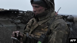 Un soldado ucraniano usa su teléfono móvil en primera línea cerca de Bájmut, en la región ucraniana de Donetsk, parcialmente ocupada por las fuerzas rusas, el 11 de marzo de 2023.