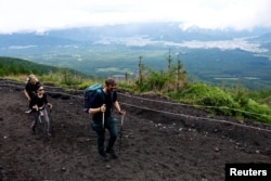 Pendaki berjalan di Jalur Fuji Yoshida Guchi pada hari pertama musim pendakian di lereng Gunung Fuji, di Fujiyoshida, Prefektur Yamanashi, Jepang, 1 Juli 2024. (Foto: Reuters)