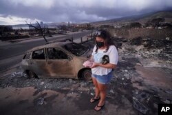Summer Gerling recoge su alcancía, que encontró entre los escombros de su casa después del incendio forestal del 10 de agosto de 2023 en Lahaina, Hawái.