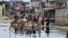 People cross floodwaters in the Pompage district of Kinshasa, Democratic Republic of Congo, on Jan. 9, 2024, following heavy rains. Regional flooding left some 350,000 people in need of humanitarian aid in neighboring Republic of Congo.