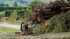 Orang-orang berdiri di samping puing-puing di daerah yang terkena banjir setelah Topan Gabrielle dekat Napier, Selandia Baru, 16 Februari 2023. (AFP)