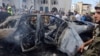 People and Lebanese army members stand near a burned car after an Israeli strike on the outskirts of the southern port city of Sidon, according to two Palestinian sources, in Lebanon, Aug. 21, 2024. 