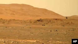 FILE - This April 30, 2021, image taken by the Mars Perseverance rover shows the Ingenuity helicopter, right, flying over the surface. Data gathered from the planet indicate there could be quite a bit of water well below the surface. (NASA via AP)