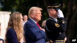 Misty Fuoco, left, sister of Nicole Gee, and Republican presidential nominee former President Donald Trump place their hands over their heart after placing a wreath in honor of Sgt. Nicole Gee at Arlington National Cemetery, Aug. 26, 2024. 