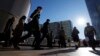 FILE - Commuters walk in a passageway during a rush hour at Shinagawa Station in Tokyo, Feb. 14, 2024. 