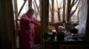 A woman sweeps broken window glass in her flat after the explosion of a downed Russian drone in a yard among residential buildings in Kyiv, Ukraine, on Nov. 25, 2023. 