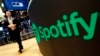 FILE - A trading post sports the Spotify logo on the floor of the New York Stock Exchange, April 3, 2018. Spotify said Monday, Dec. 4, 2023 it's cutting 17% of its global workforce as it tries to slash costs while focusing on profitabilty.