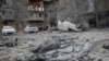 Residents stand near their apartment building and vehicles damaged during a Russian missile strike during Russia's attack on Ukraine, in Kharkiv, Ukraine, on Dec. 8, 2023.