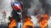 A demonstrator holds up a Haitian flag during protests demanding the resignation of Prime Minister Ariel Henry in Port-au-Prince, Haiti, March 1, 2024.