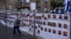 A man passes by a fence with photographs of hostages, mostly Israeli civilians who were abducted during the Oct. 7, unprecedented Hamas attack on Israel, in Ramat Gan, Israel, Nov. 22, 2023.