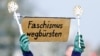 FILE - A protester displays toilet brushes and a sign reading, "Brush fascism away" at a demonstration against the Alternative for Germany (AfD) party, right-wing extremism and for the protection of democracy in Hamburg, Germany, Feb. 25, 2024. 