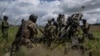 Sejumlah tentara Ukraina bersiap menembak posisi Rusia dengan howitzer M777 yang dipasok AS di wilayah Kharkiv, Ukraina, 14 Juli 2022. (Foto: Evgeniy Maloletka/AP Photo)