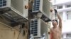FILE - A handyman works on air conditioning units as summer temperatures soar in Hong Kong on Aug. 10, 2024. 