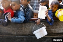 Palestinian children wait to receive food cooked by a charity kitchen amid shortages of food supplies in Rafah in the southern Gaza Strip, Jan. 16, 2024.