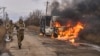 In this photo provided by Ukraine's military, Ukrainian soldiers pass by a bus burning after a Russian drone hit it near Bakhmut, Donetsk region, Ukraine, Nov. 23, 2023.