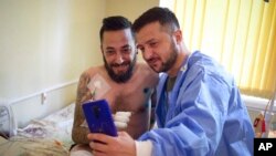 En esta imagen, distribuida por la oficina de prensa de las presidencia de Ucrania, el presidente del país, Volodymyr Zelenskyy (derecha), se toma una selfie con un soldado herido, en un hospital en Odesa, el 29 de julio de 2022.