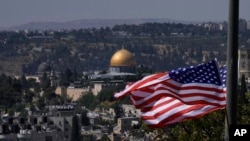 Con el santuario de la Cúpula de la Roca al fondo, las banderas estadounidenses ondean antes de la visita del presidente Joe Biden a Jerusalén.