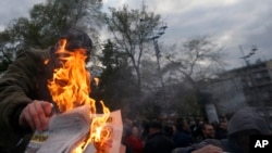 Demonstrant spaljuje novine na čijoj je naslovnoj strani novoizabrani predsednik i premijer Srbije Aleksandar Vučić, tokom četvrtog po redu "Protesta protiv diktature", Beograd, 6. aprila 2017. (AP Photo/Darko Vojinovic)