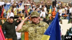 Un soldado saluda mientras asiste a una ceremonia por los soldados caídos en acción en el cementerio de Lychakiv en Lviv, en el oeste de Ucrania, el 24 de agosto de 2022, marcando seis meses desde el comienzo de la invasión rusa de Ucrania y la independencia nacional.