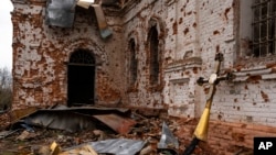 Una cruz de metal que solía estar en la parte superior de la cúpula se encuentra fuera de la iglesia dañada en Lukashivka, en el norte de Ucrania, el 22 de abril de 2022.