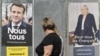 Women walk past campaign posters of French President and La Republique en Marche (LREM) party candidate for re-election Emmanuel Macron (L) and French far-right party Rassemblement National (RN) presidential candidate Marine Le Pen, in Eguisheim, eastern France, April 21, 2022.