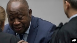 Former Ivory Coast President Laurent Gbagbo greets his legal team as he enters the courtroom of the International Criminal Court in The Hague, Netherlands, Jan. 15, 2019, where judges acquitted Gbagbo and ex-government minister Charles Ble Goude for lack 