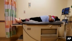 Brooklynn Chiles, 8, lies on an exam room table during a followup visit to Children's National Hospital in Washington, Feb. 11, 2022. 