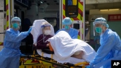 Trabajadores médicos con ropas de protección trasladan a una paciente de COVID-19 en Hong Kong el 4 de marzo de 2022. 