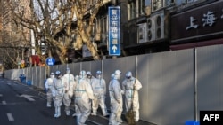 Obreros en ropas de protección trabajan en un área de la ciudad china de Shanghái donde se registraron nuevos casos de COVID-19 el 15 de marzo de 2022.