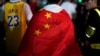 中国上海，在NBA布鲁克林篮网队和洛杉矶湖人队的表演赛之前，一名身穿勒布朗·詹姆斯球衣的男子在梅赛德斯-奔驰球场外用中国国旗包裹自己（2019年10月10日）。