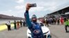 El conductor Bubba Wallace se se hace un autorretrato con su teléfono junto a sus compañeros, quienes empujaron su auto al frente de la Pista Talladega antes del inicio de la carrera de autos de la Copa NASCAR el 22 de junio de 2020.