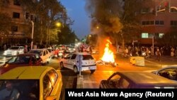FILE - A police motorcycle burns during a protest over the death of Mahsa Amini, a woman who died after being arrested by the Islamic republic's "morality police", in Tehran, Iran, Sept. 19, 2022.