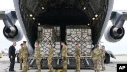 El secretario de Agricultura, Tom Vilsack, a la izquierda, saluda a los miembros de la tripulación de un C-17 que entregó un avión cargado de fórmula para bebés en el Aeropuerto Internacional de Indianápolis en Indianápolis, el domingo 22 de mayo de 2022.