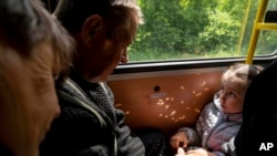 Una niña con sus abuelos de Lyman viajan en el autobús durante la evacuación cerca de Lyman, Ucrania, el 11 de mayo de 2022.