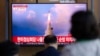 FILE - People watch a news program reporting about North Korea's missile launch showing a file image, at a train station in Seoul, South Korea, May 25, 2022.