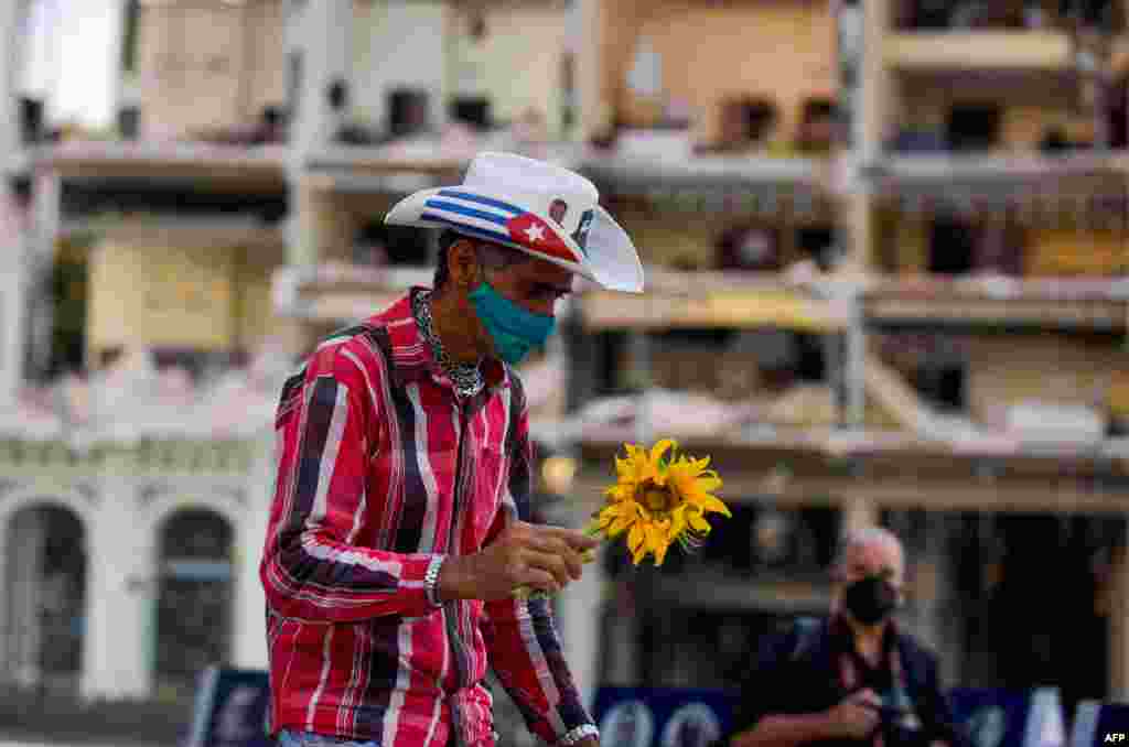 Un hombre lleva un girasol a una vigilia por las víctimas del accidente del Hotel Saratoga en La Habana, el 13 de mayo de 2022.