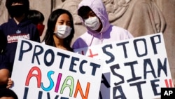 Esta foto de archivo del 20 de marzo de 2021 muestra a personas con carteles mientras asisten a un mitin para apoyar campaña en contra del odio referente a personas de origen asiático, en el Monumento Logan Square en Chicago.
