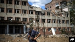 Un residente de pie junto a un edificio muy dañado en un bombardeo ruso enfrente de su casa en Bakhmut, en el este de Ucrania, el martes 24 de mayo de 2022. (AP Foto/Francisco Seco)
