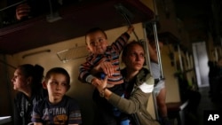 Yana Skakova y su hijo Yehor, que huyeron de Lysychansk, se sientan en un tren de evacuación en la estación de tren de Pokrovsk, en el este de Ucrania, el 28 de mayo de 2022.