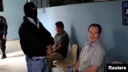 ARCHIVO - Guillermo Alfredo Benavides, quien forma parte del grupo de 17 exmilitares acusados de matar a 6 sacerdotes jesuitas en 1989, espera en la corte para ser notificado de la solicitud de extradición a España, en San Salvador, en abril de 2016.