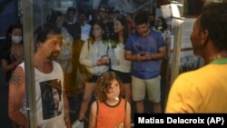 Los visitantes al Museo Pele en Santos, Brasil, observan una estatua de tamaño natural de Pelé, con una camiseta amarilla brillante de la selección de Brasil, exhibida en una vitrina el 30 de diciembre de 2022.